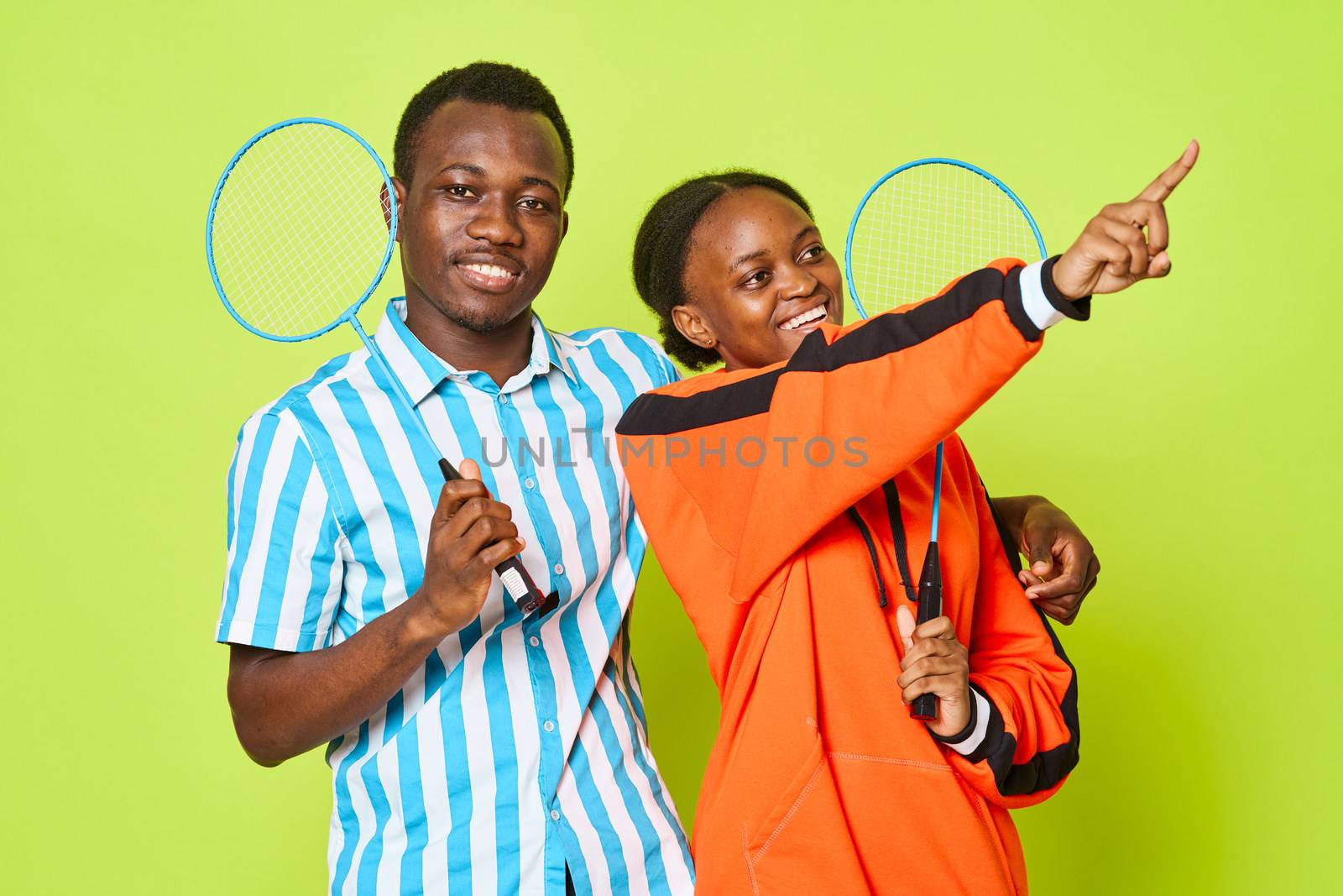 A cheerful young couple of African appearance tennis rackets joy smile