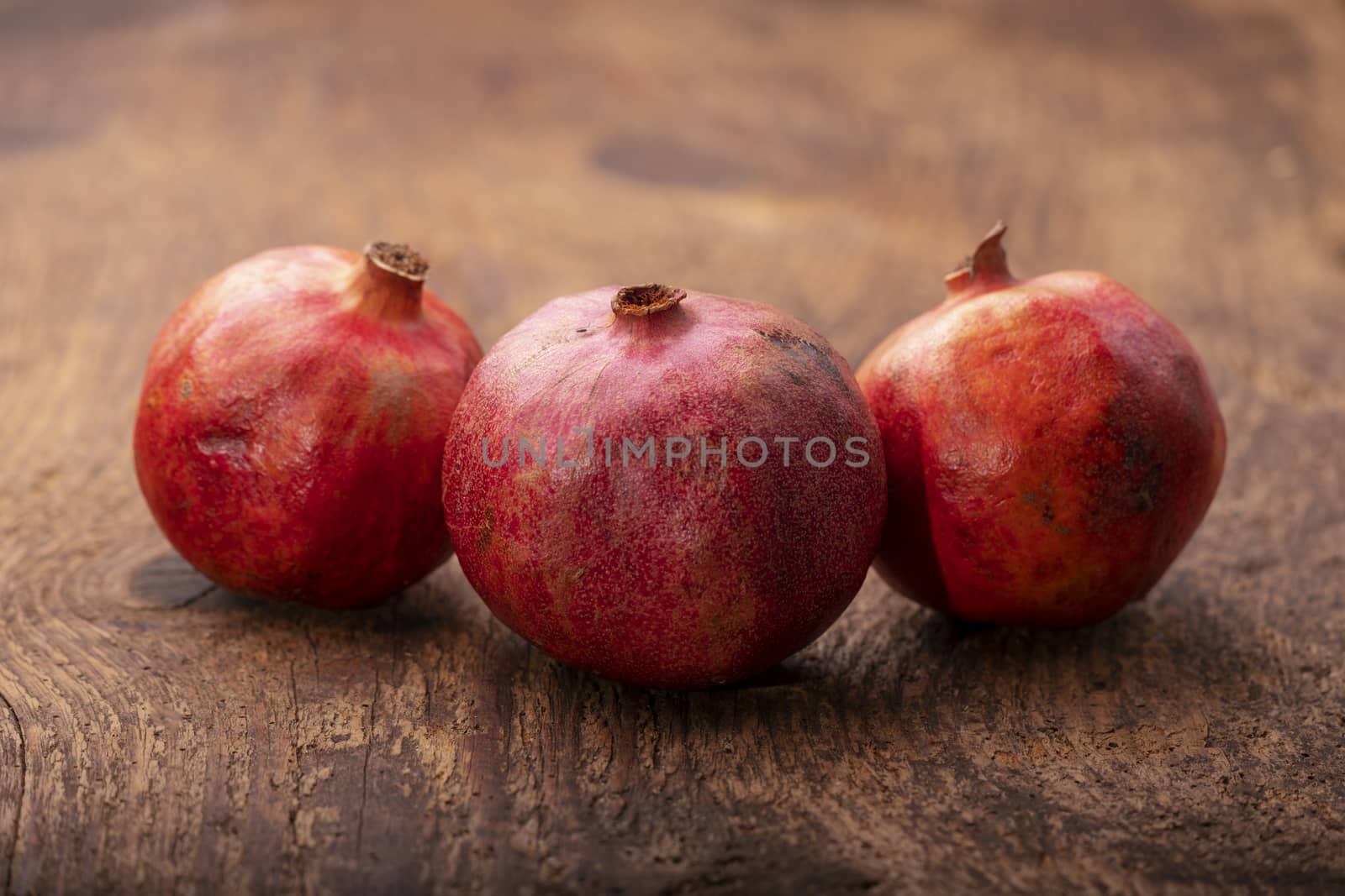 three pomegranades on dark wood