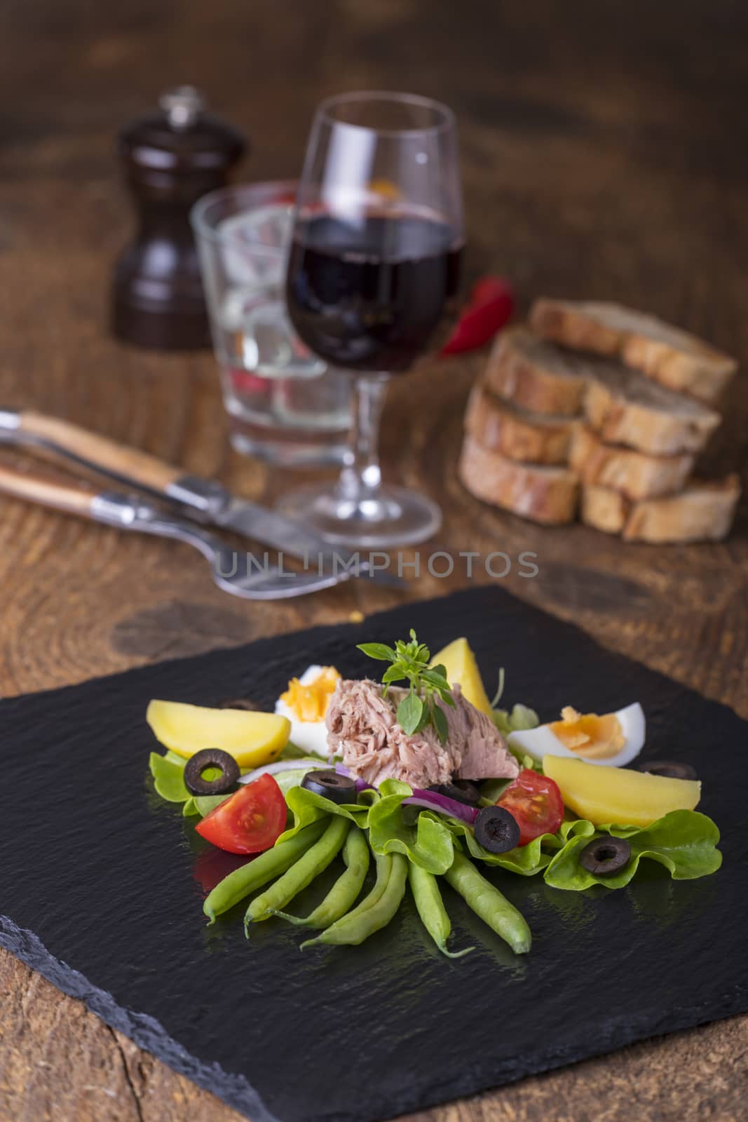 salad nicoise on a wooden background by bernjuer
