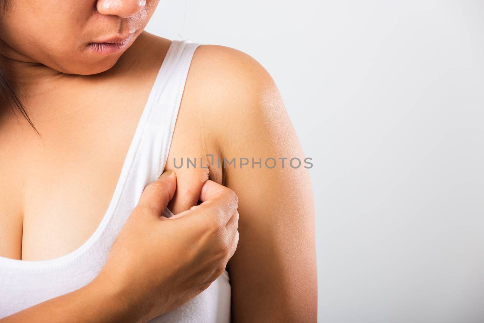 Close up of Asian woman pulling excess fat on her skin underarm she problem armpit fat underarm wrinkled skin, studio isolated on white background, Healthy overweight excess body concept