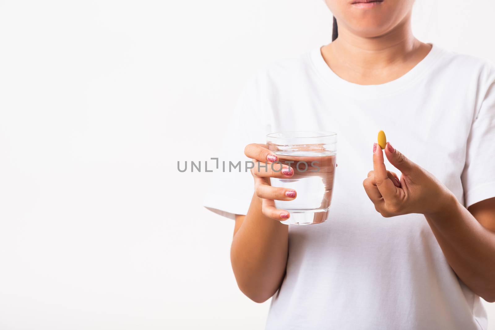 Closeup young Asian woman hold fish oil vitamin drugs in hand ready take medicines with a glass of water, studio shot isolated on white background, Healthcare and medical pharmacy concept