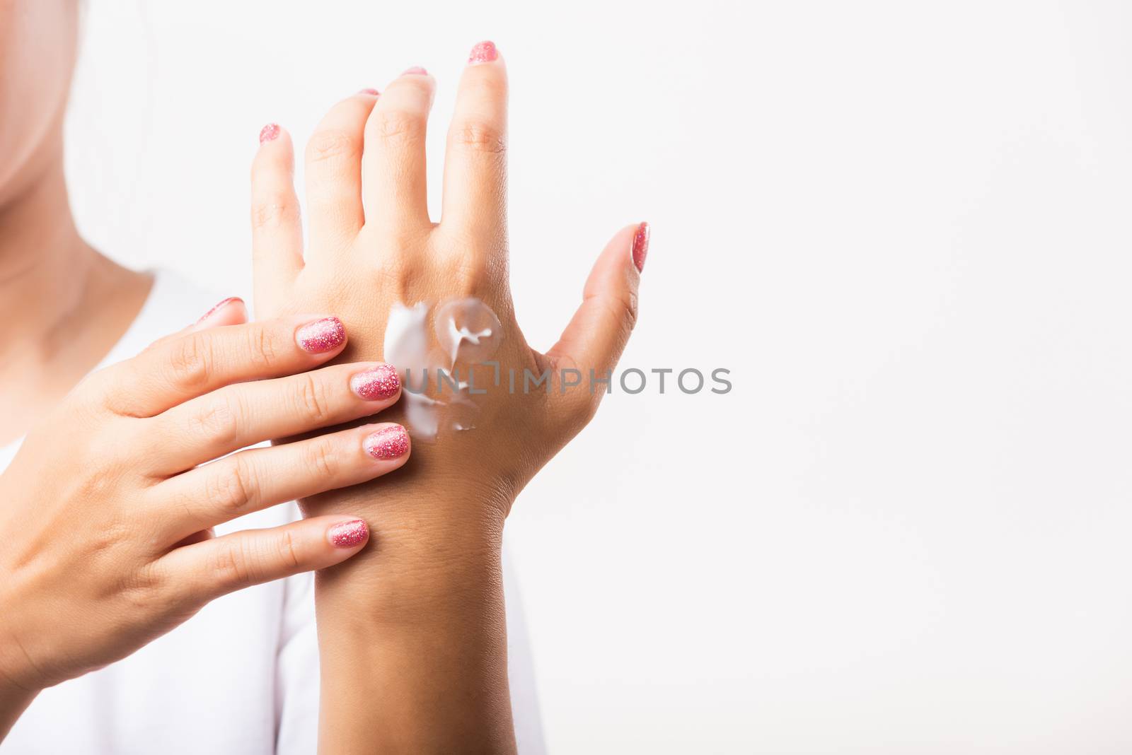 Closeup young Asian woman applying lotion cosmetic moisturizer cream on her behind the palm skin hand, studio shot isolated on white background, Healthcare medical and hygiene skin body care concept