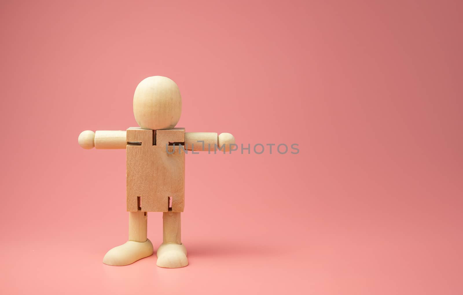 A Wooden doll on pink background. 
keep distance concept.