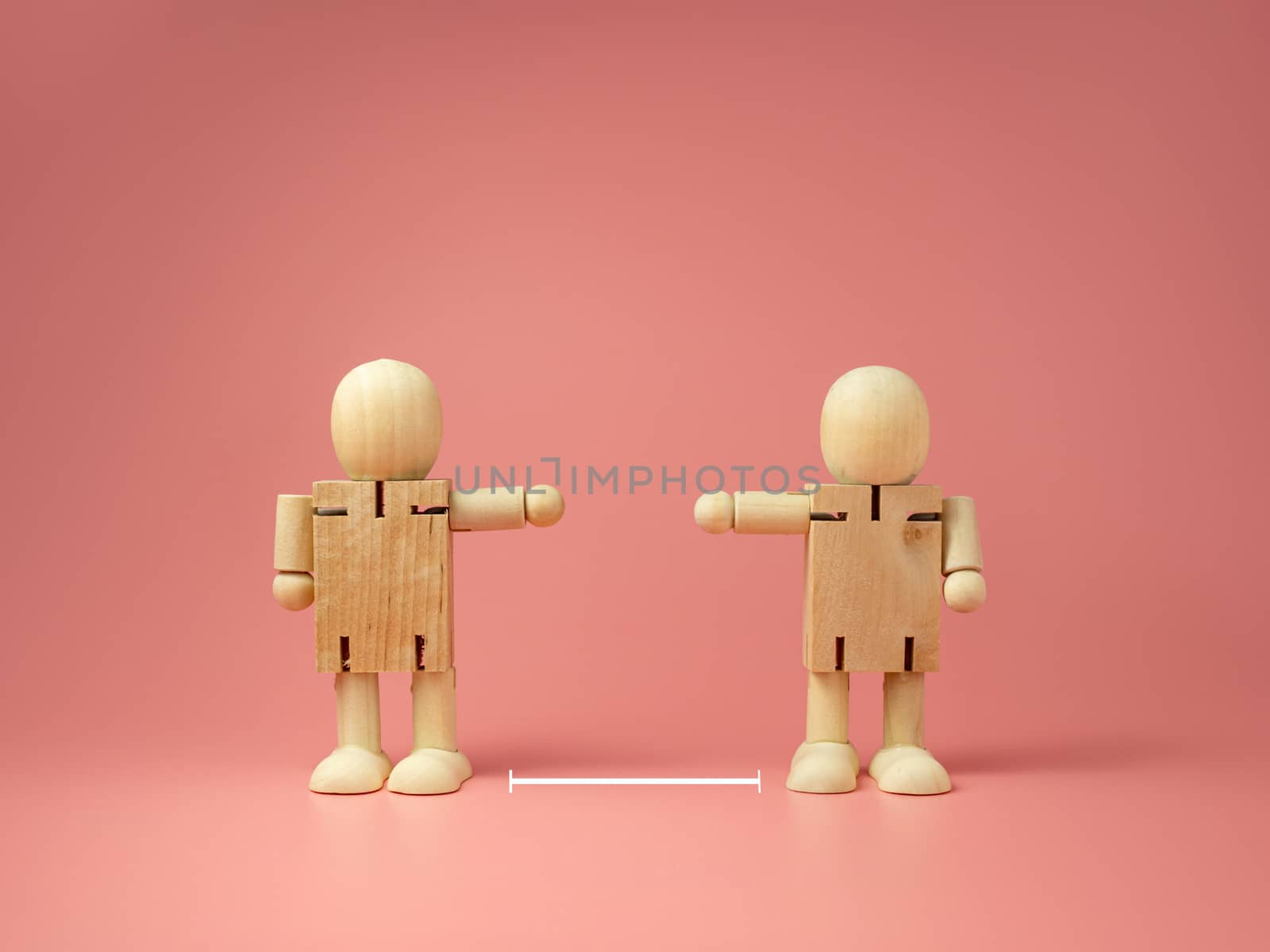 Two wooden doll on pink background. 
keep distance concept.
preventive measures.
infection control.