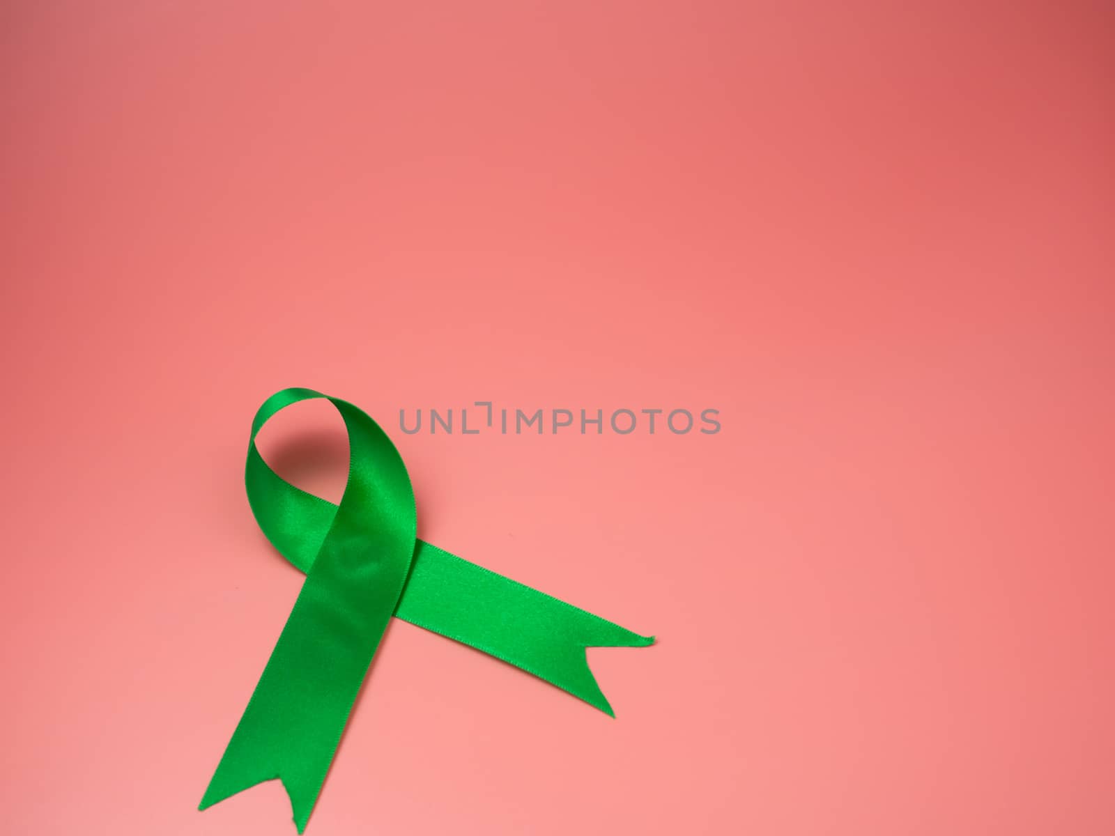 Green ribbon symbol on a pink background. by Unimages2527