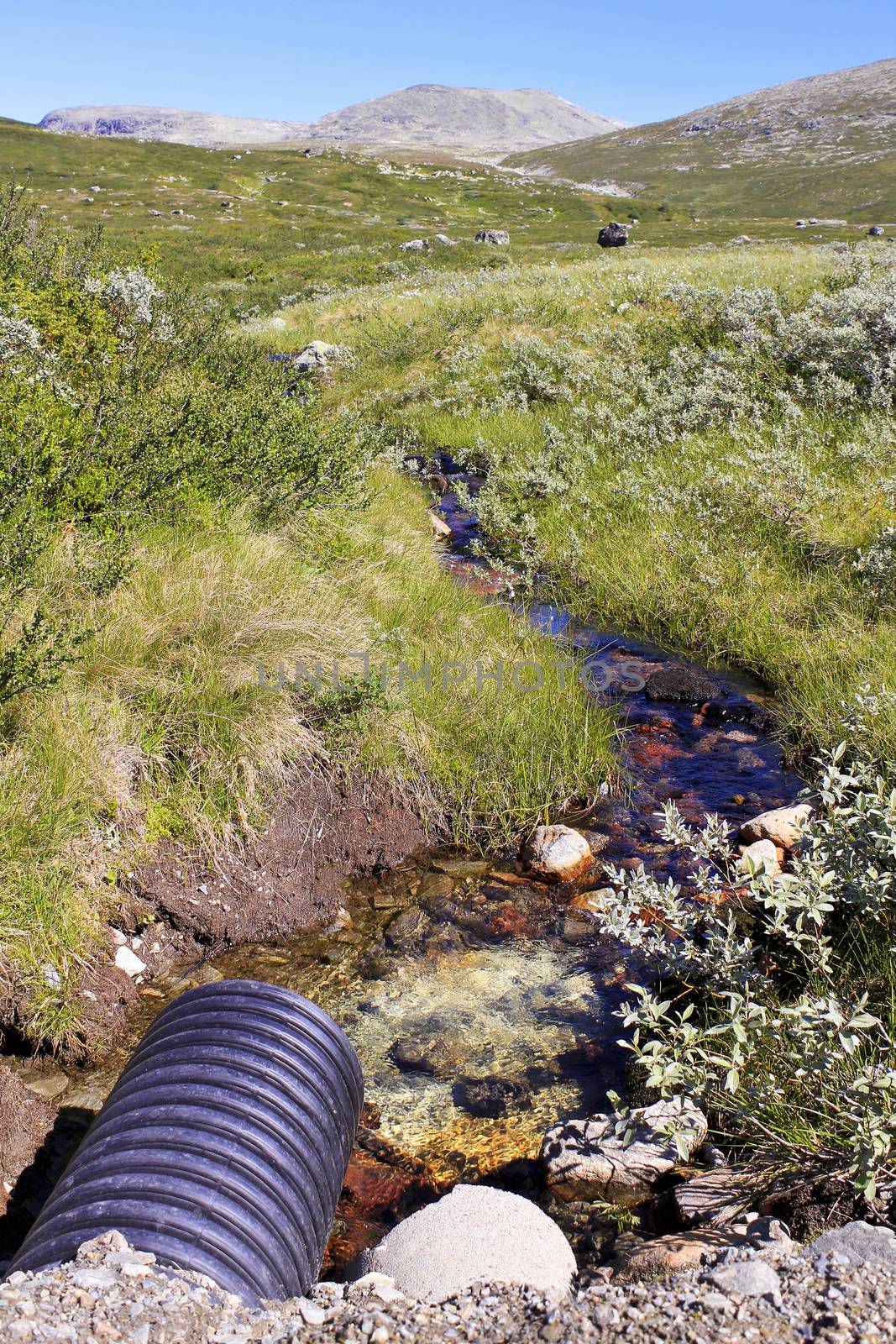 Small red color river by the Vavatn lake. Summer landscape in Hemsedal, Buskerud, Norway.