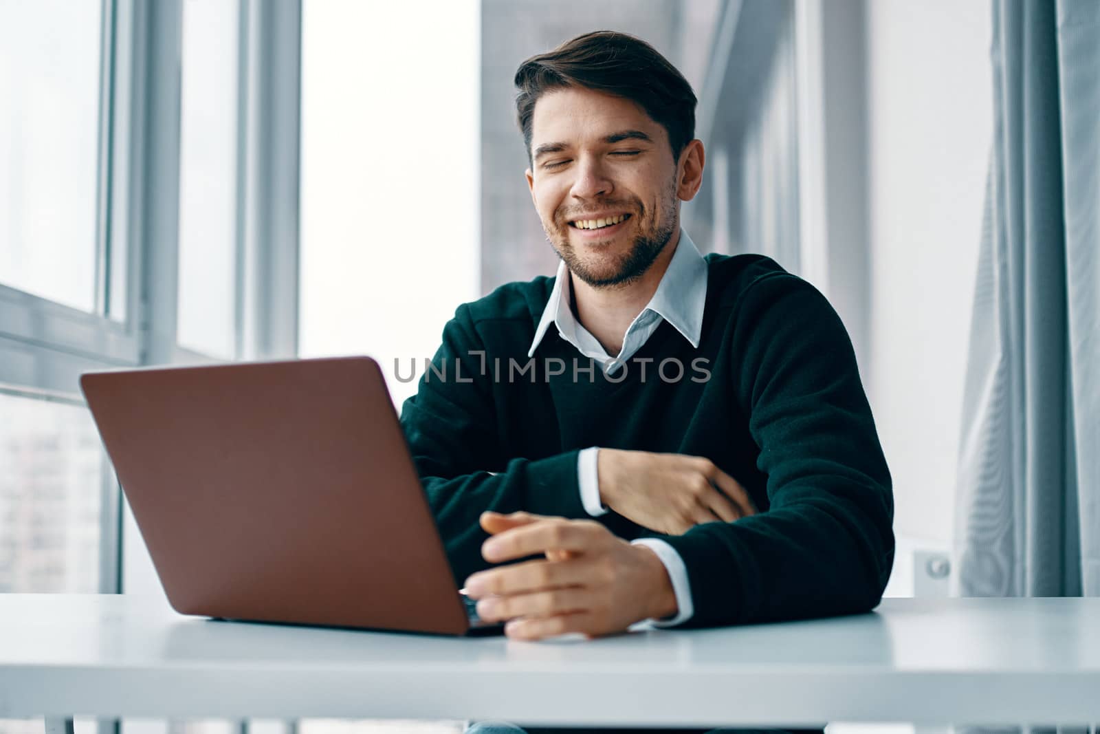 man at work looking at a laptop and sitting near the window by SHOTPRIME