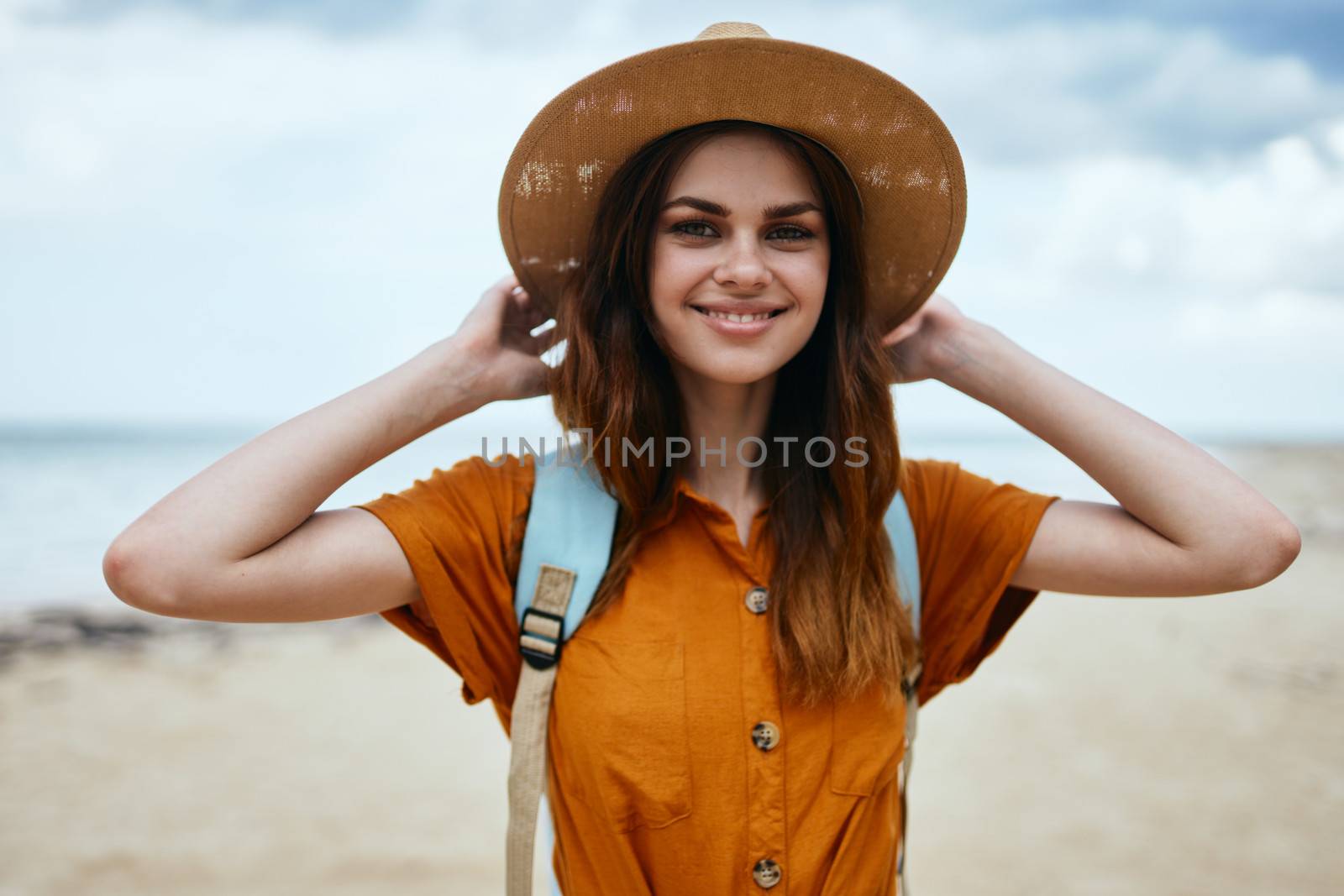 Happy woman model on the island with a hat on her head and a backpack on her back