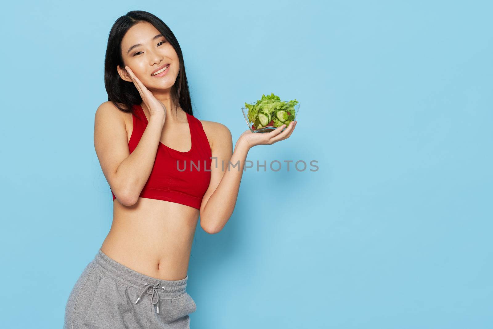 Beautiful woman of Asian appearance slim figure plate with salad vegetables healthy food blue background