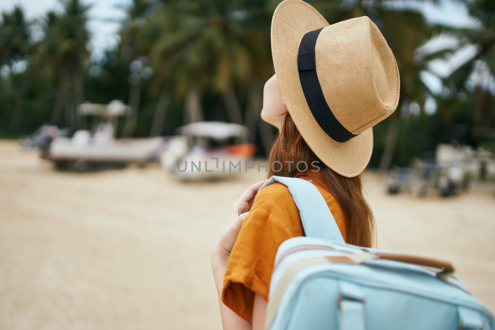 Charming traveler with a backpack and a hat on the island, rear view