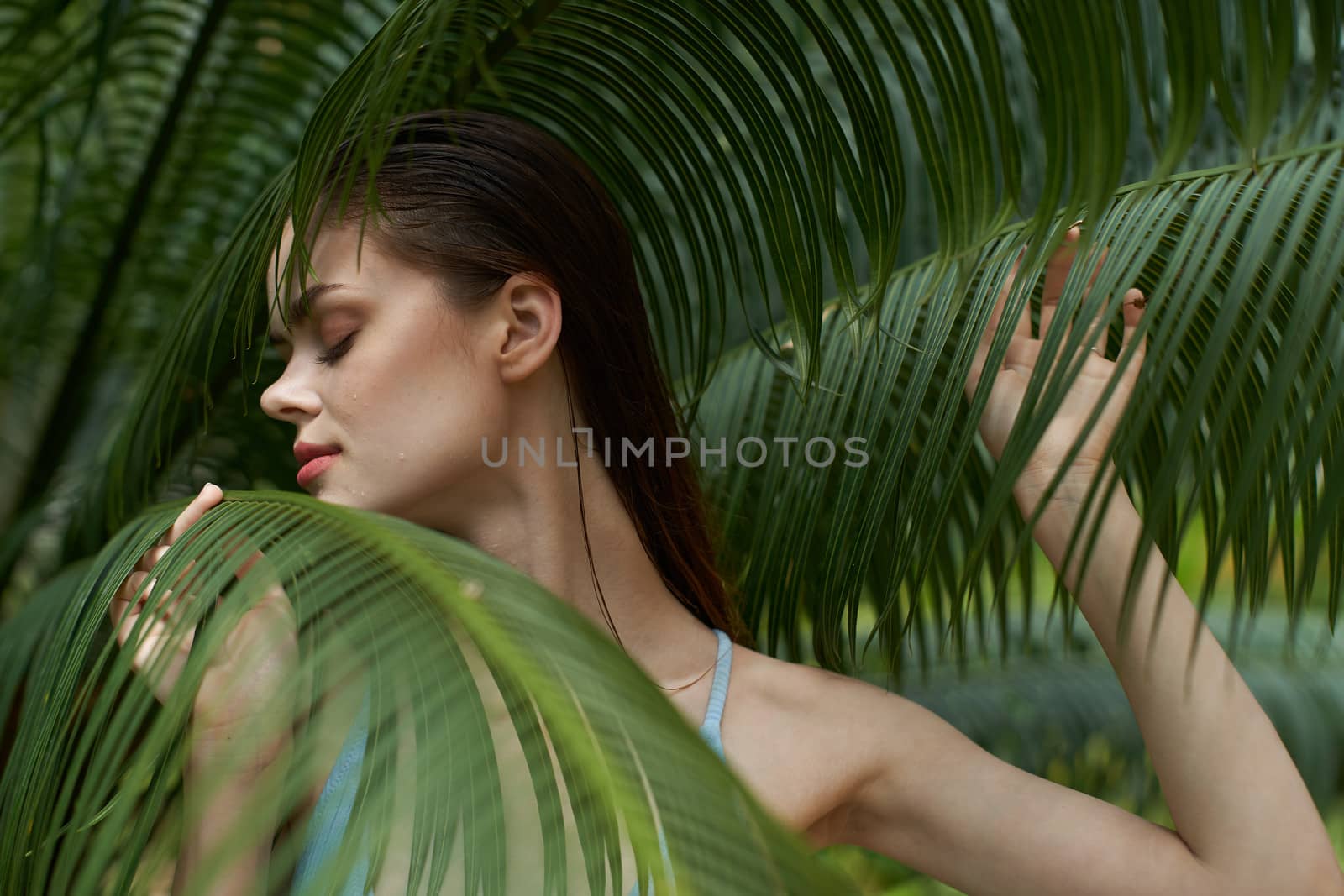 Charming woman near green leaves of bushes cropped view