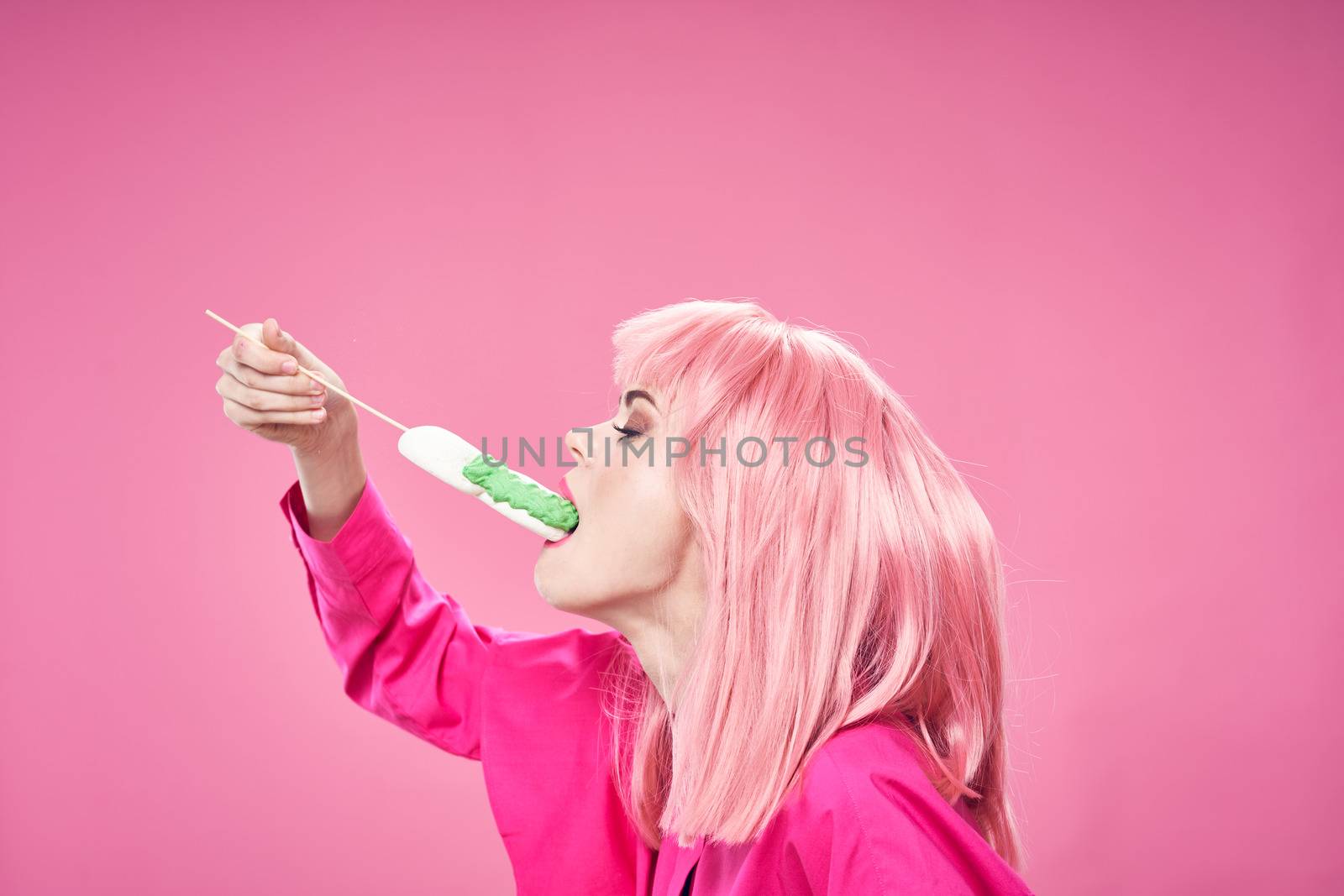 Beautiful woman in a pink shirt eats a cake on an isolated background disco party