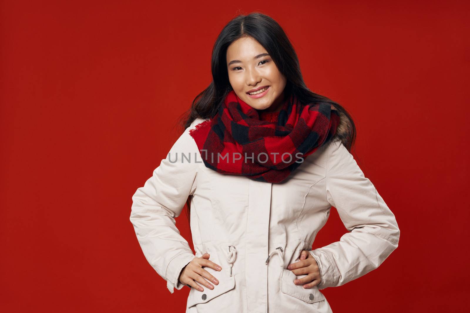 A pretty woman of Asian appearance in a warm jacket and a scarf around her neck