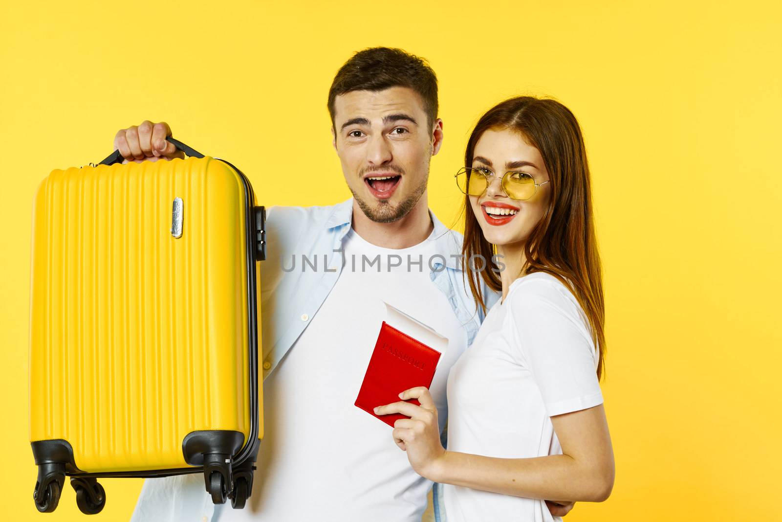 A woman with a passport and tickets is standing next to a man with a suitcase traveling by SHOTPRIME
