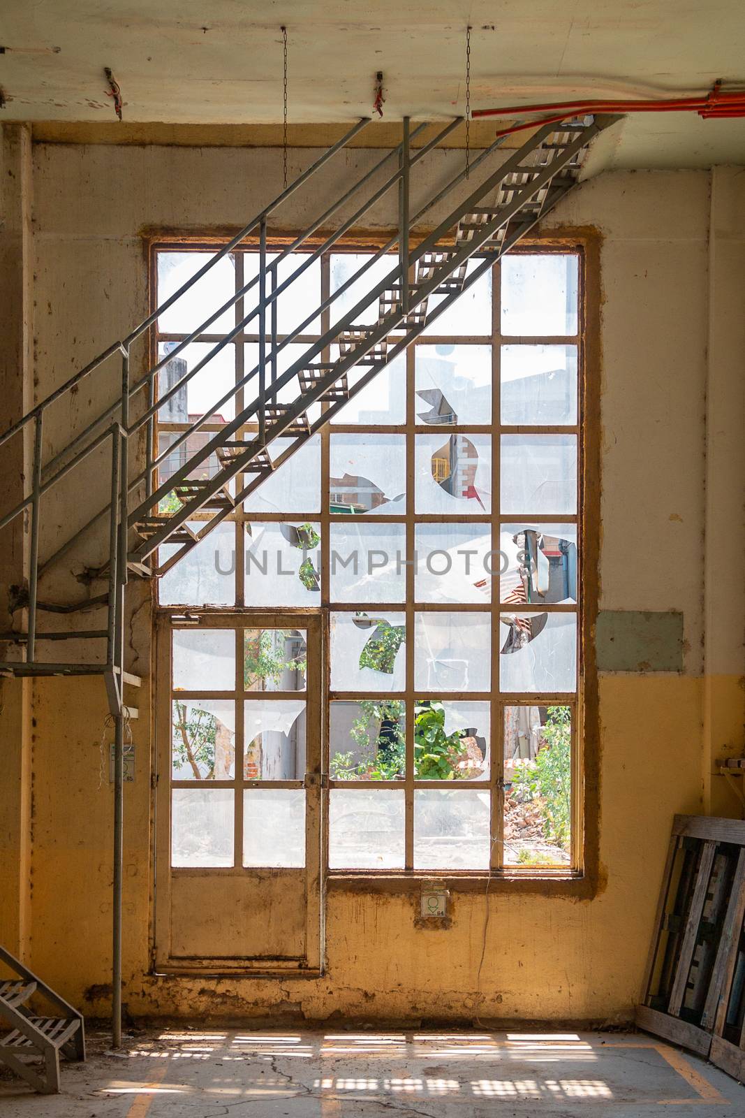 Old broken windows. with metal stairs inside a yellow building. Abandoned space