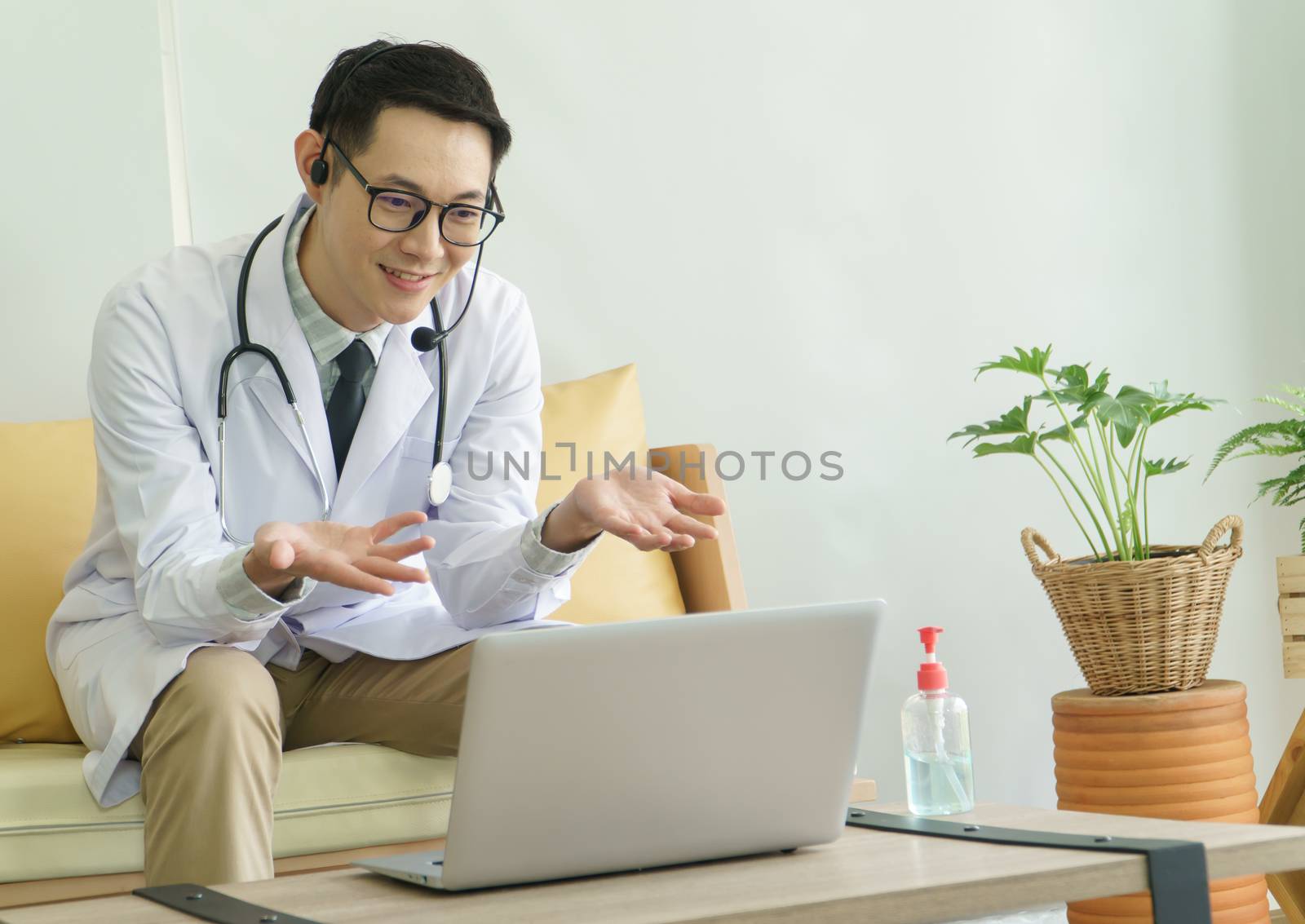 Asian male doctor is using a laptop computer to connect to the internet for online counseling. The medical profession, technology, communication, distance, and people concept