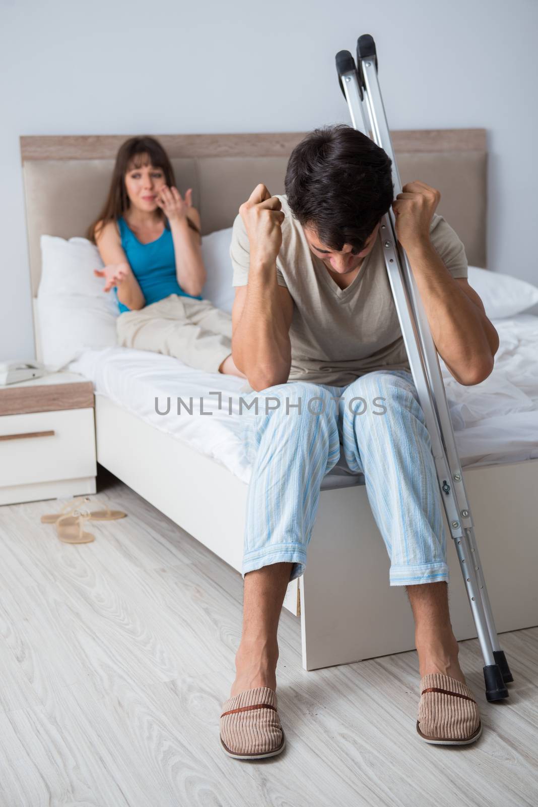 Young wife supporting husband on crutch after injury