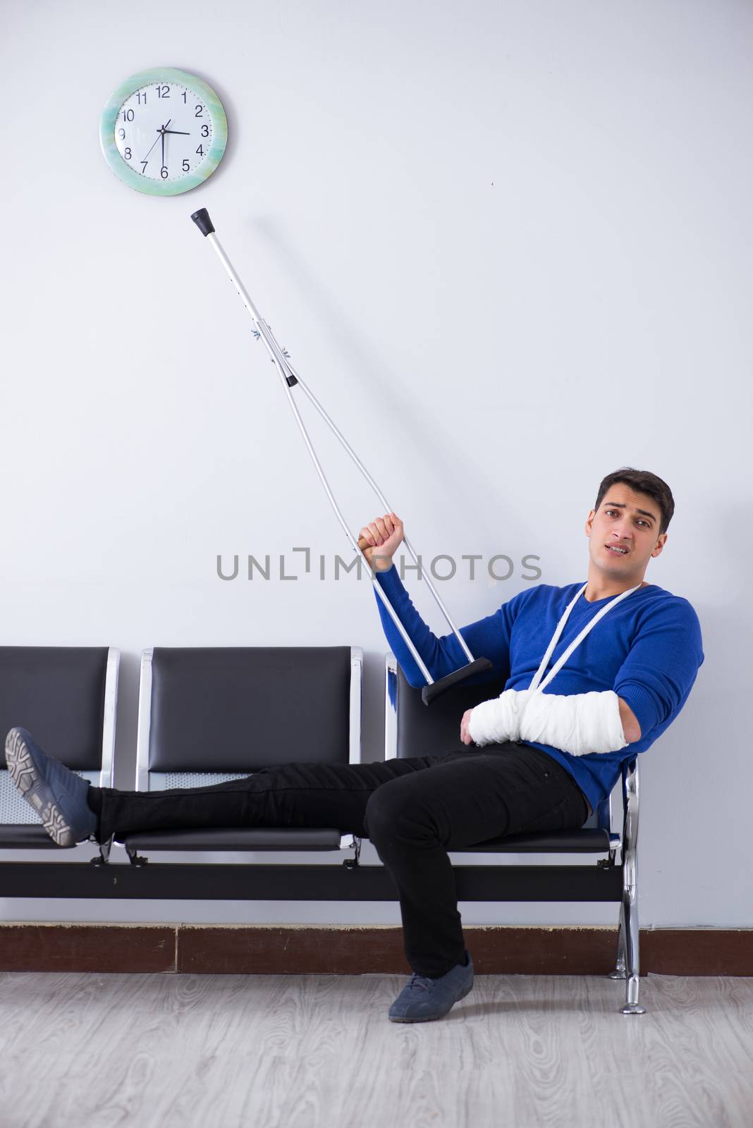 Desperate man waiting for his appointment in hospital with broken arm