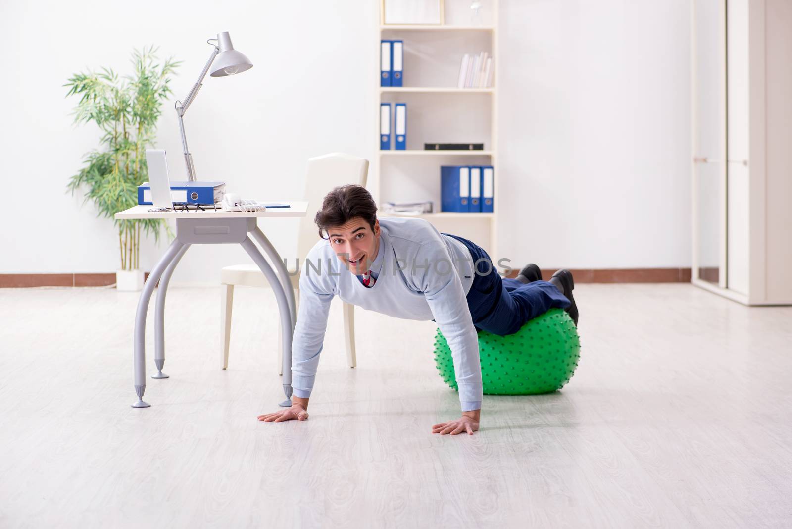 Employee exercising with swiss ball during lunch break by Elnur