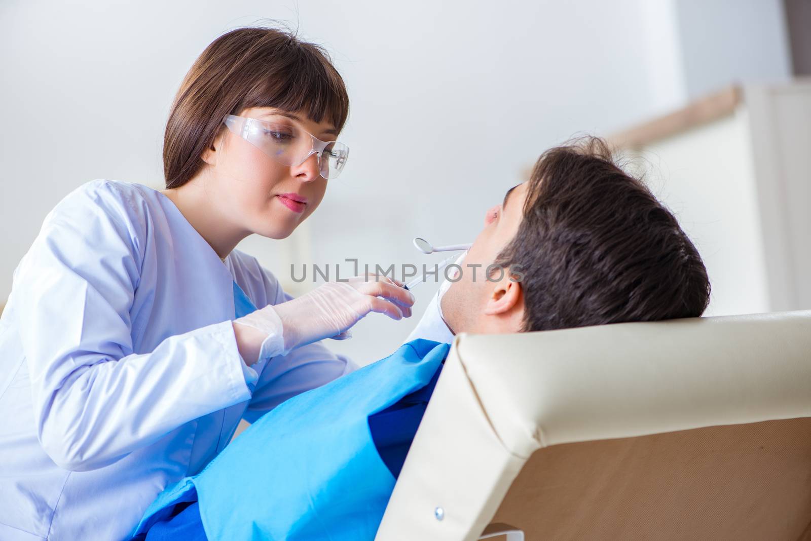 Woman dentist doctor with male patient in hospital by Elnur