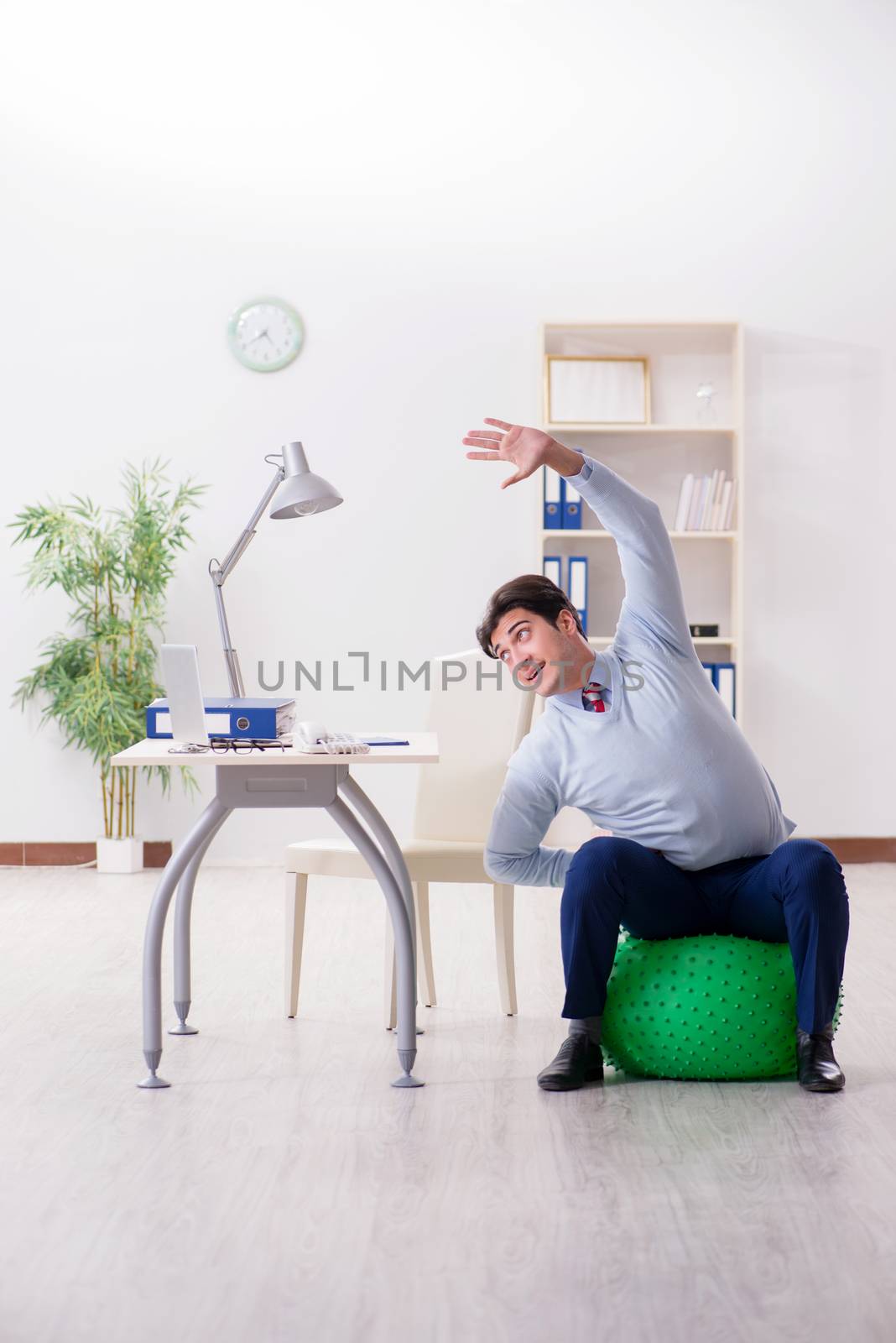Employee exercising with swiss ball during lunch break by Elnur
