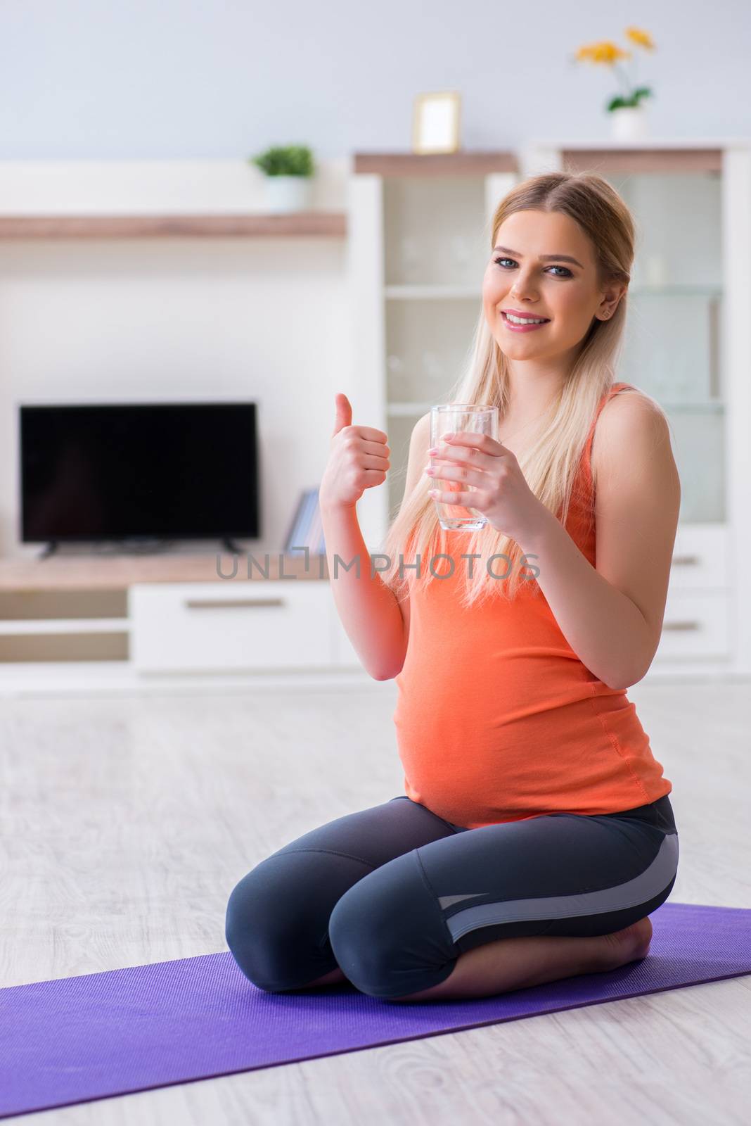 Pregnant woman doing sport exercise at home by Elnur