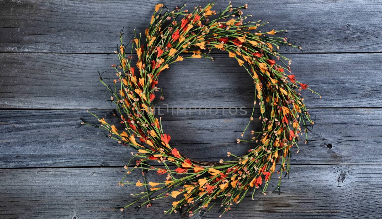 Seasonal autumn wreath with small orange flowers on vintage wooden background 