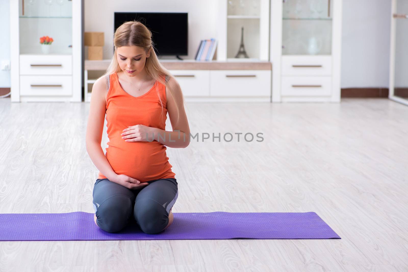 Pregnant woman doing sport exercise at home by Elnur