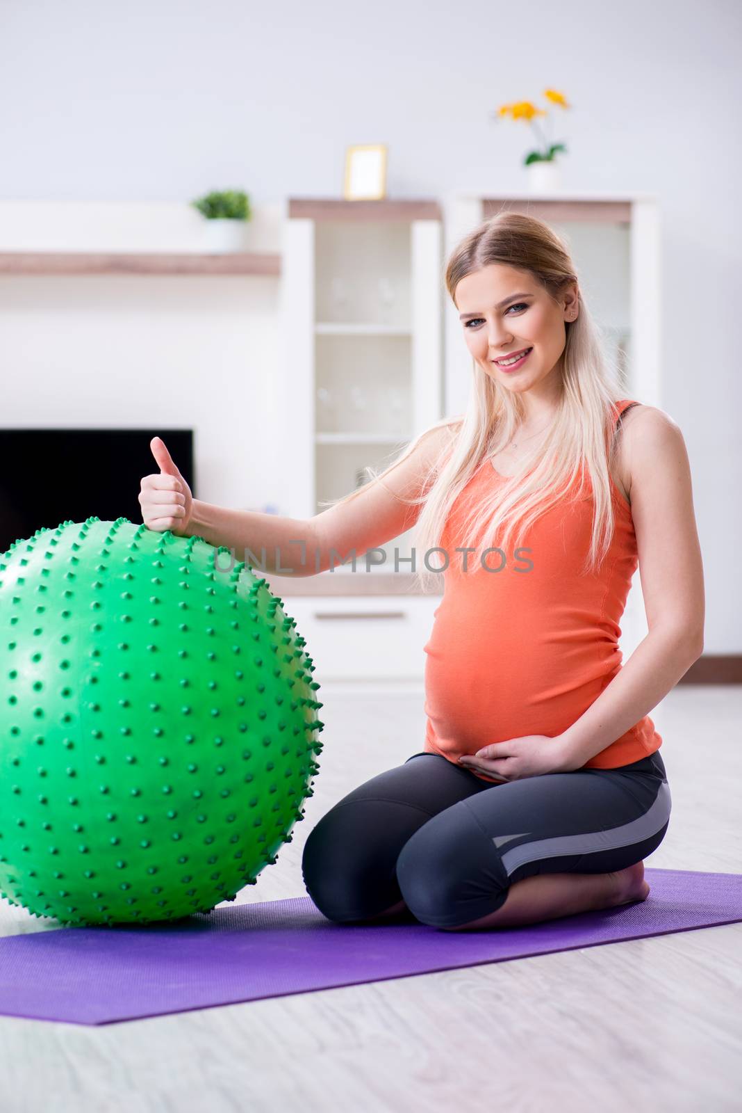 Young woman preparing for birth exercising at home by Elnur