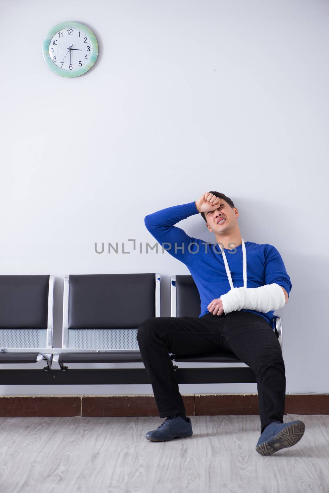 Desperate man waiting for his appointment in hospital with broken arm