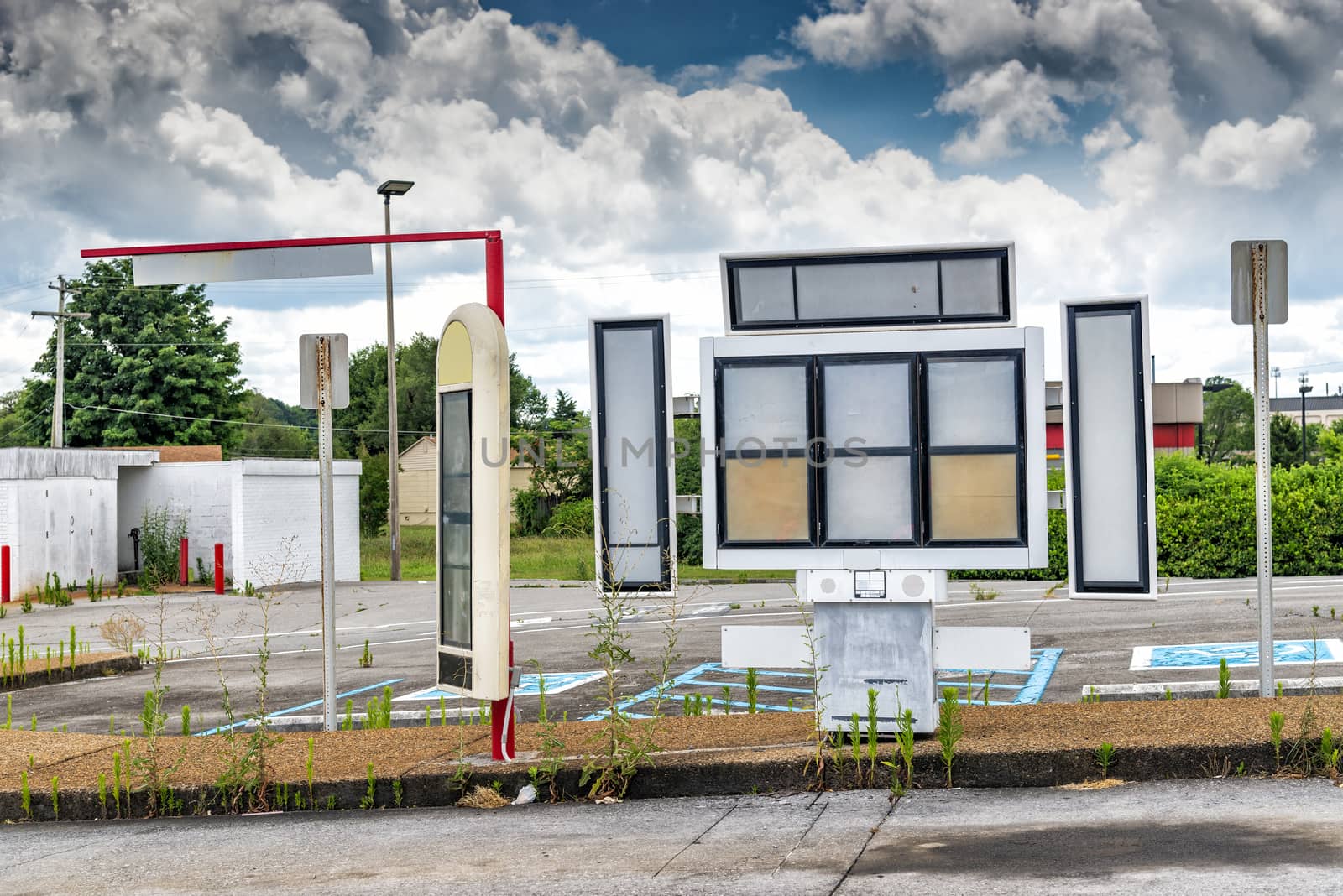 Vertical shot of the overgrown empty parking lot of a bankrupt fast food restaurant after the Pandemic.