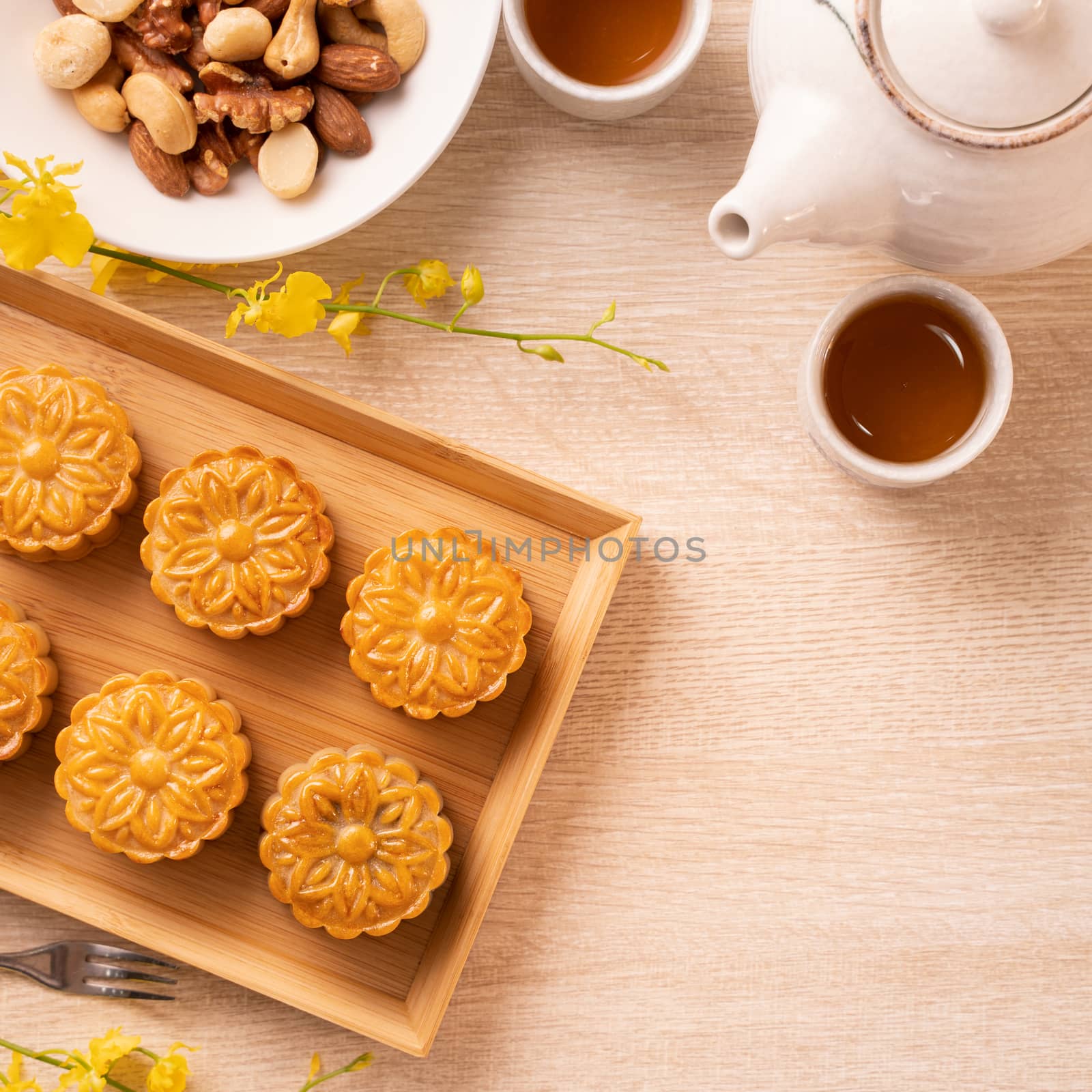 Mid-Autumn Festival holiday concept design of moon cake, mooncakes, tea set on bright wooden table with copy space, top view, flat lay, overhead shot