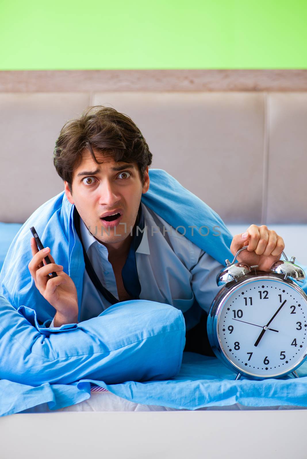 Employee in the bedroom being late for his job in time management concept