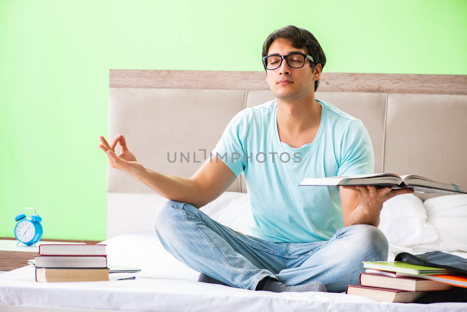 Student preparing for exams at home in bedroom sitting on the be by Elnur