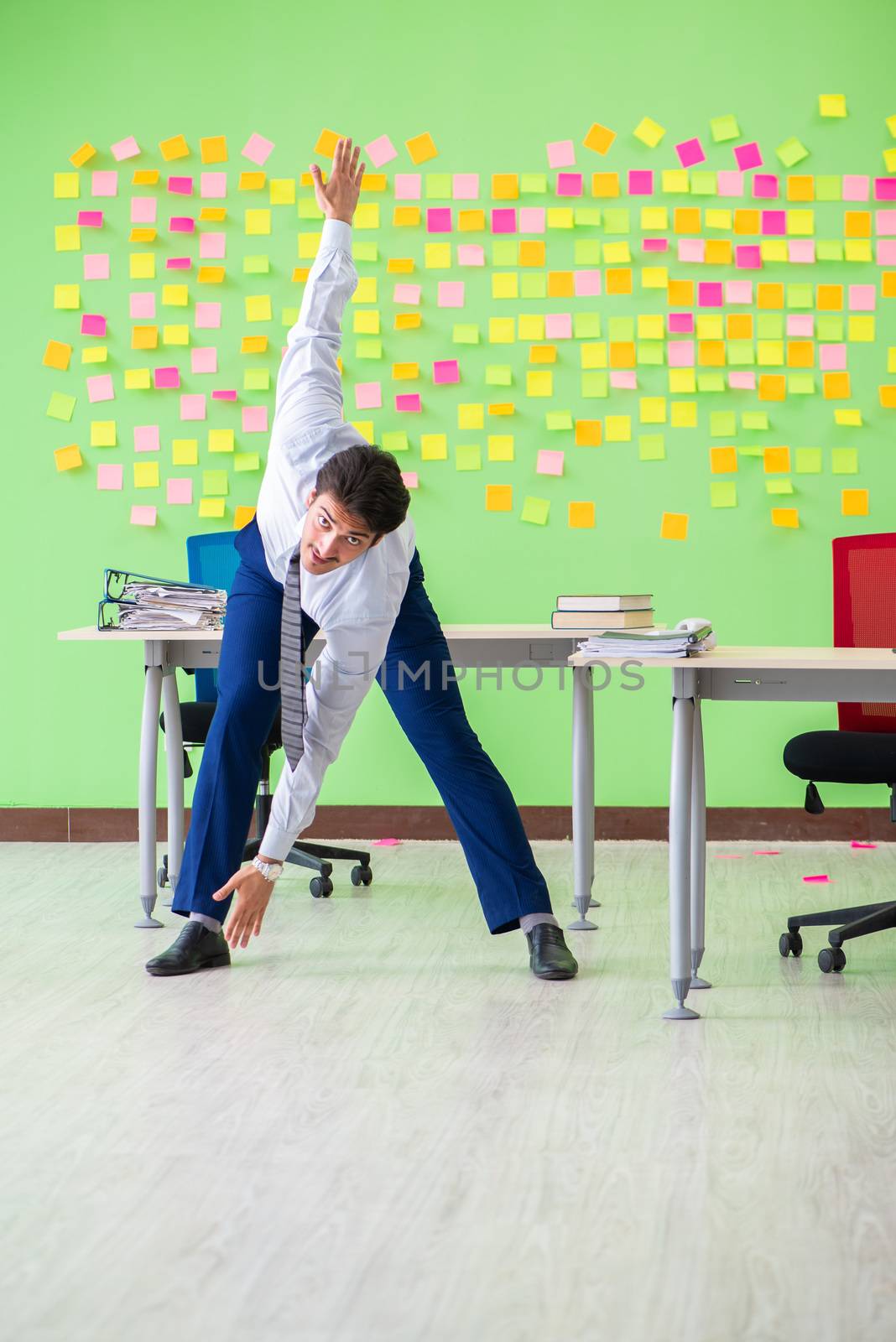 Man in the office with many conflicting priorities doing exercises  