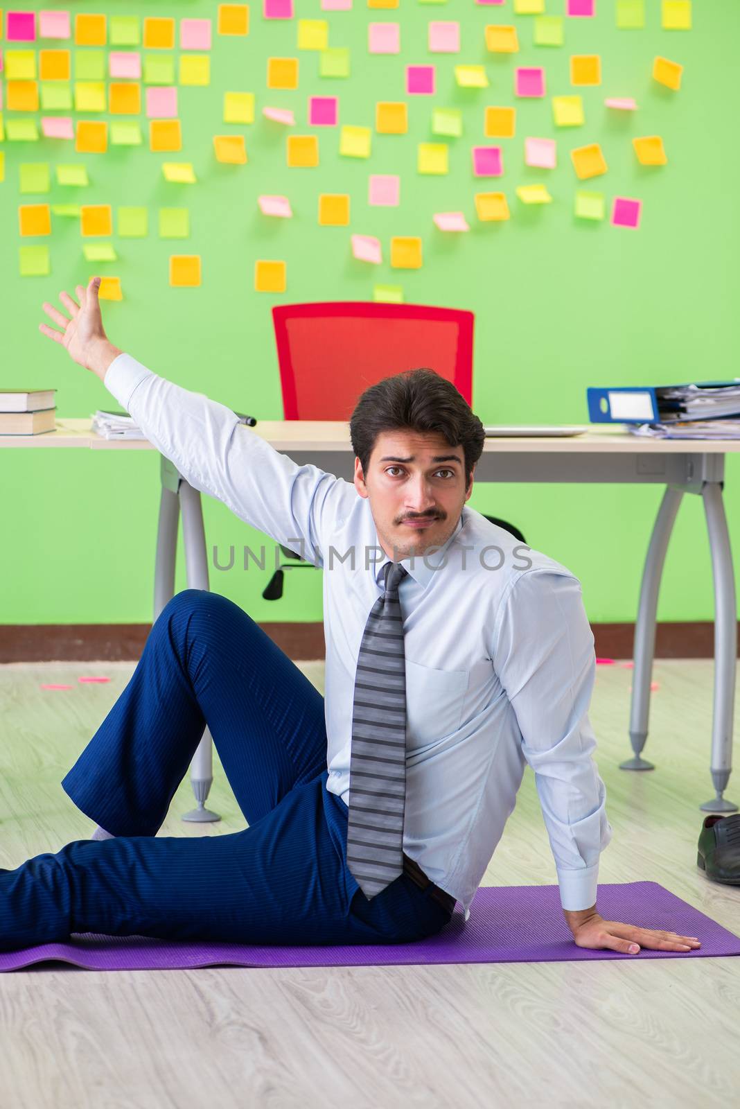 Man in the office with many conflicting priorities doing exercises