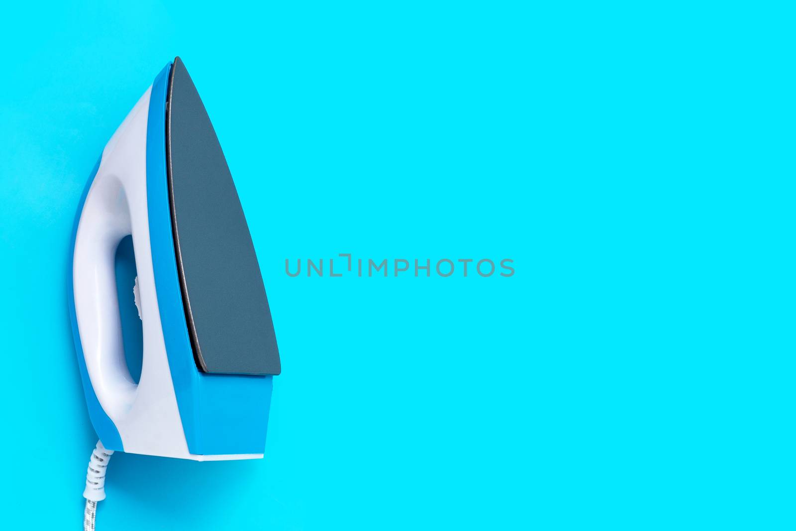 Iron on blue background. Top view with copy space