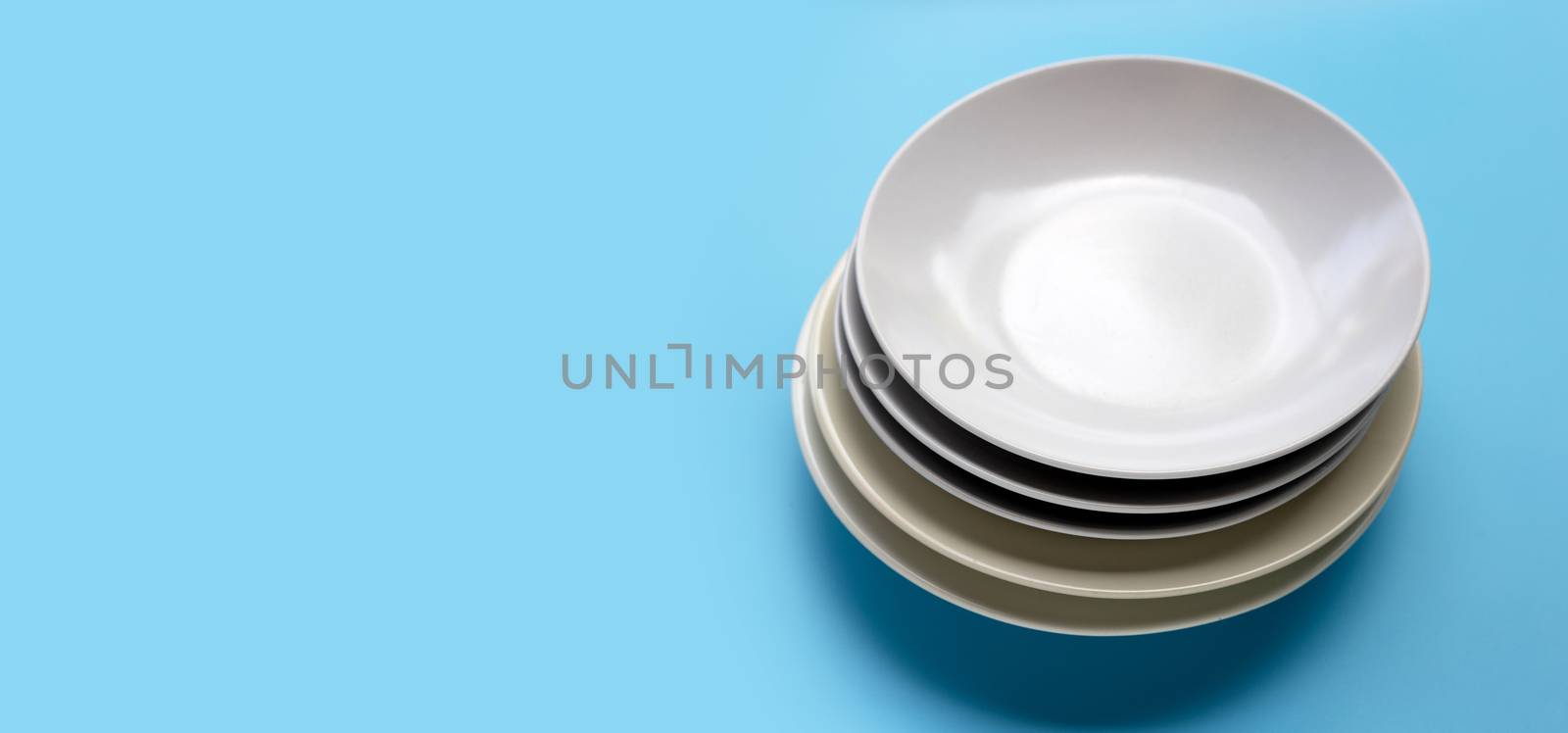 Stack of dishes on blue background. Copy space