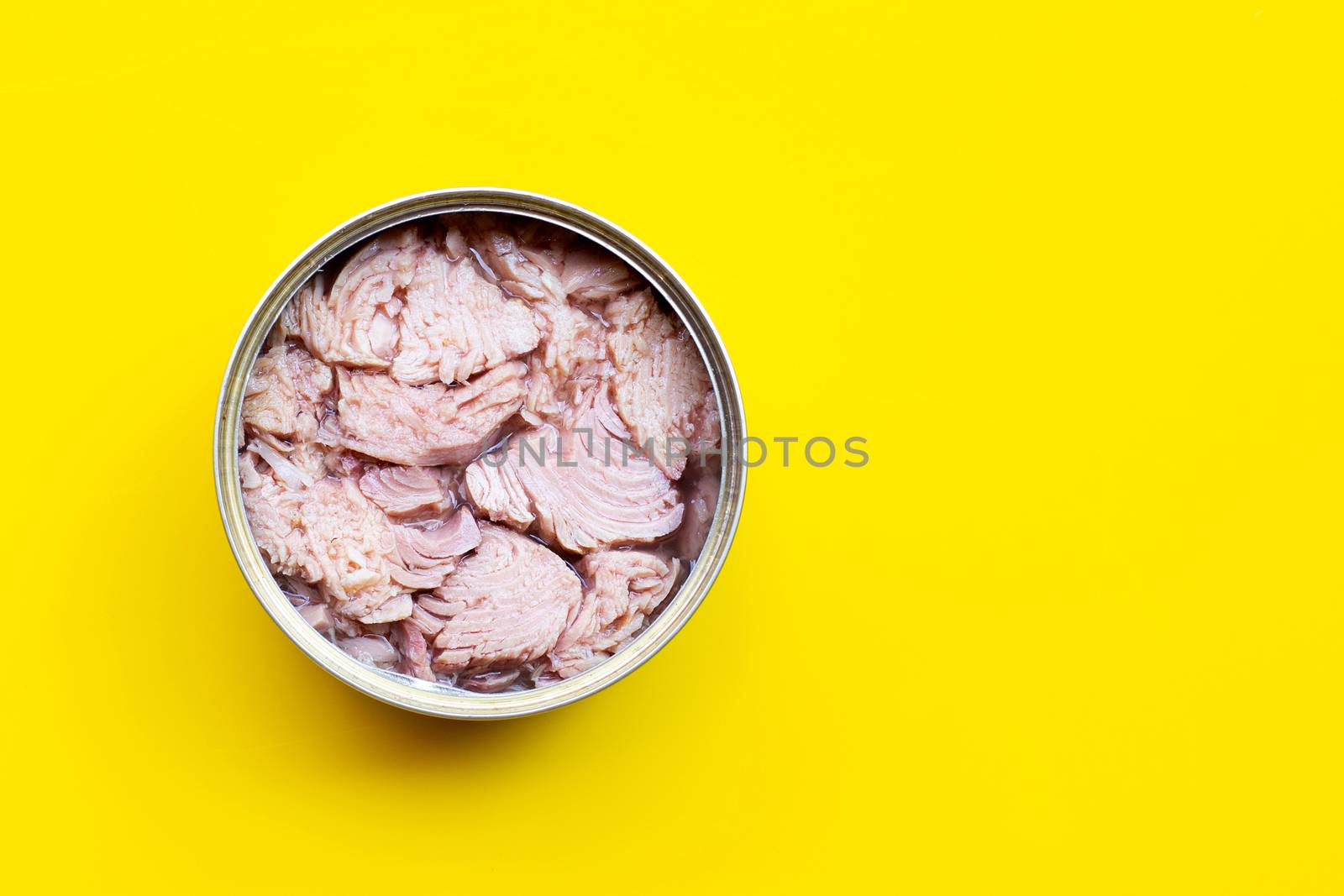 Canned tuna fish on yellow background. Copy space