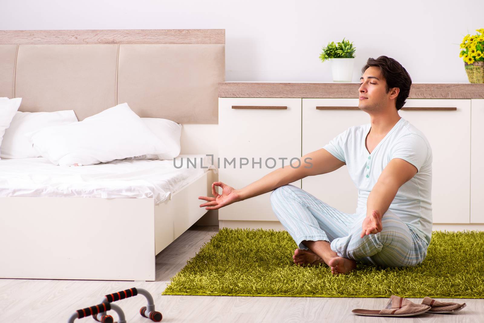Young man doing yoga in bedroom  by Elnur