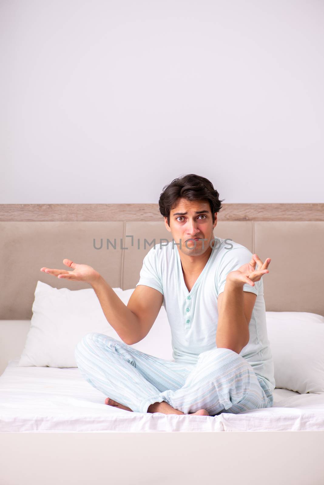 Young man doing yoga in bed