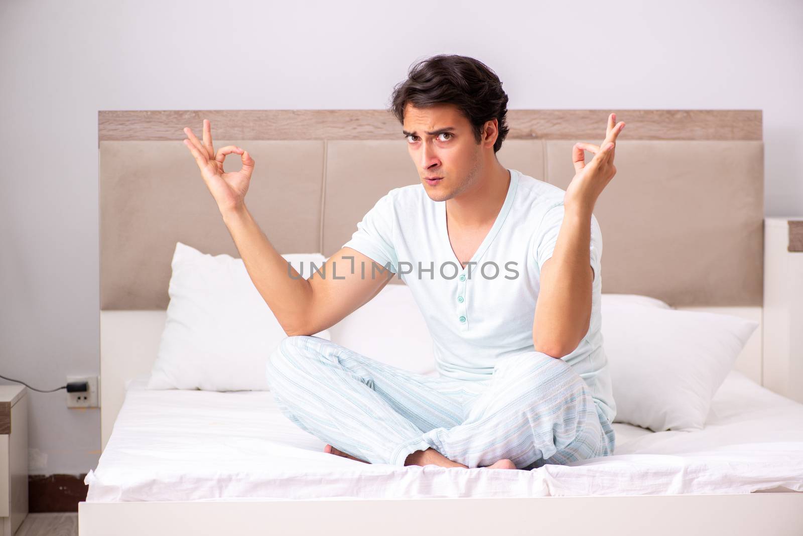 Young man doing yoga in bed