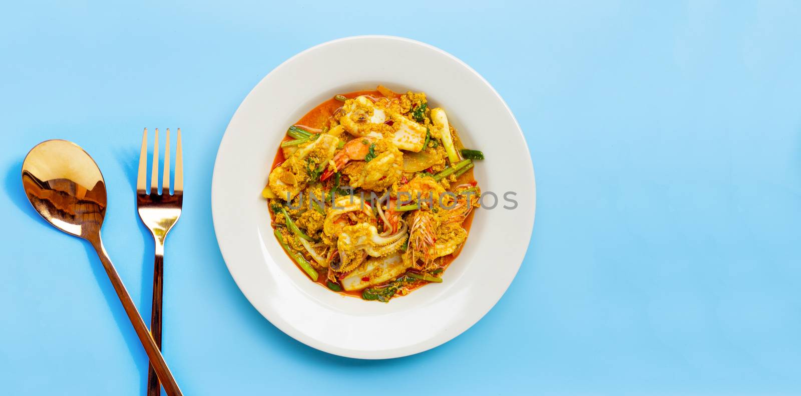 Fried seafood with curry powder on blue background