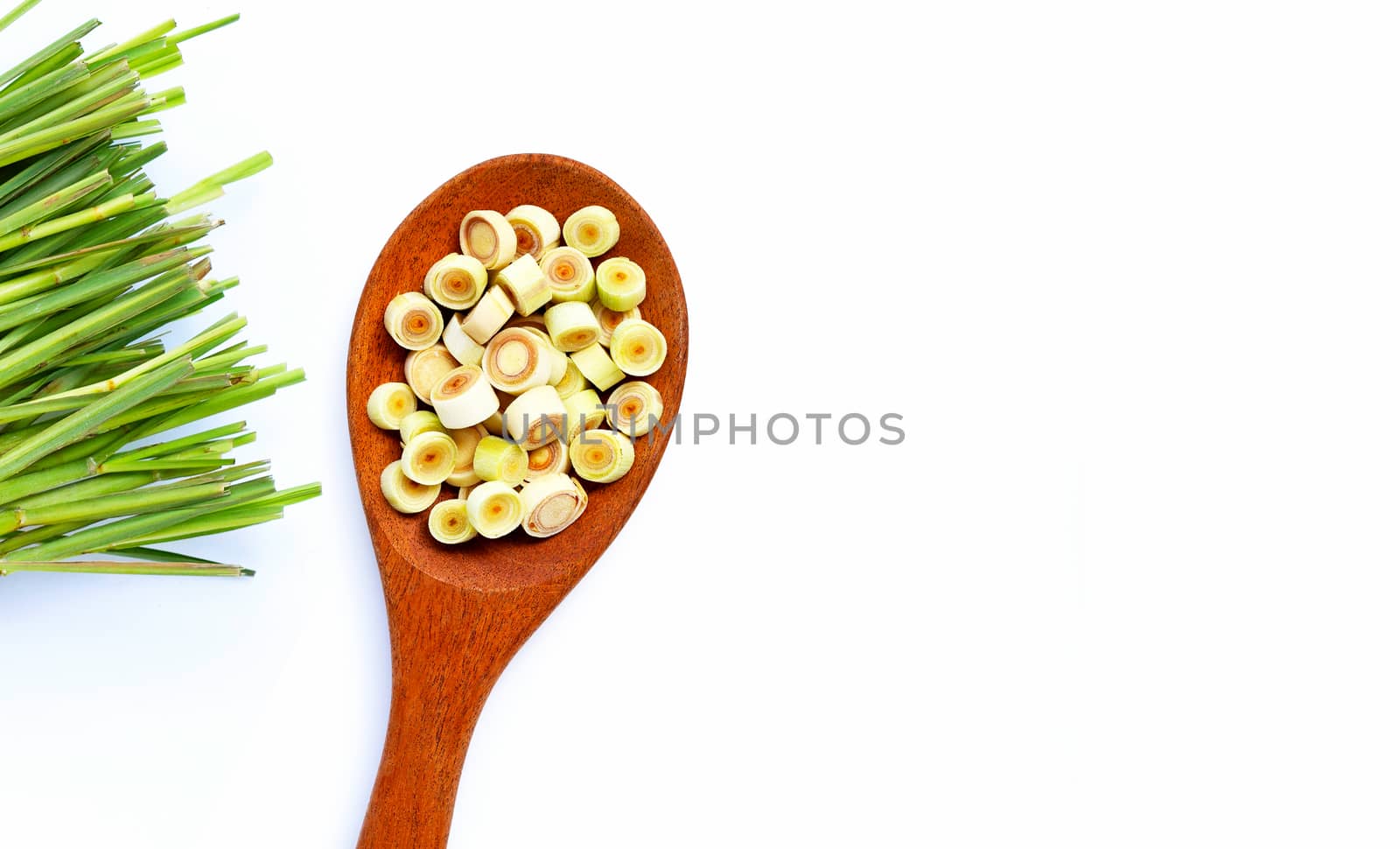 Fresh lemongrass slices on wooden spoon on white background. Copy space