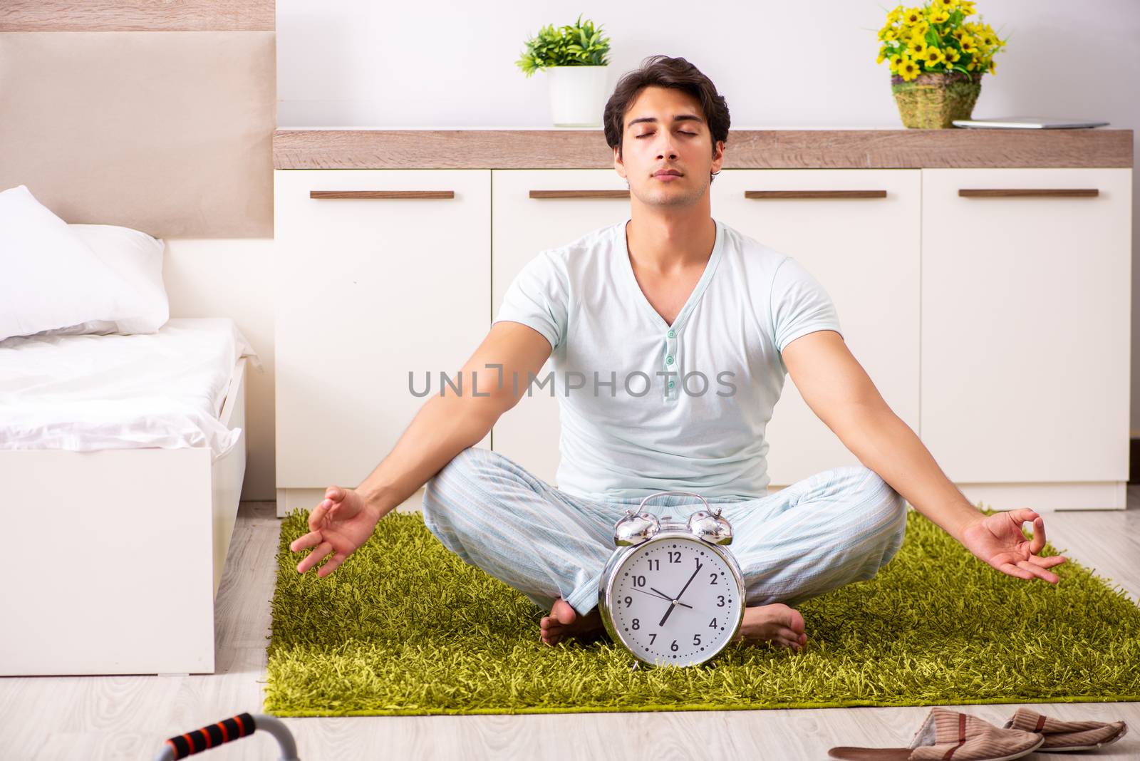 Young man doing yoga in bedroom in time management concept