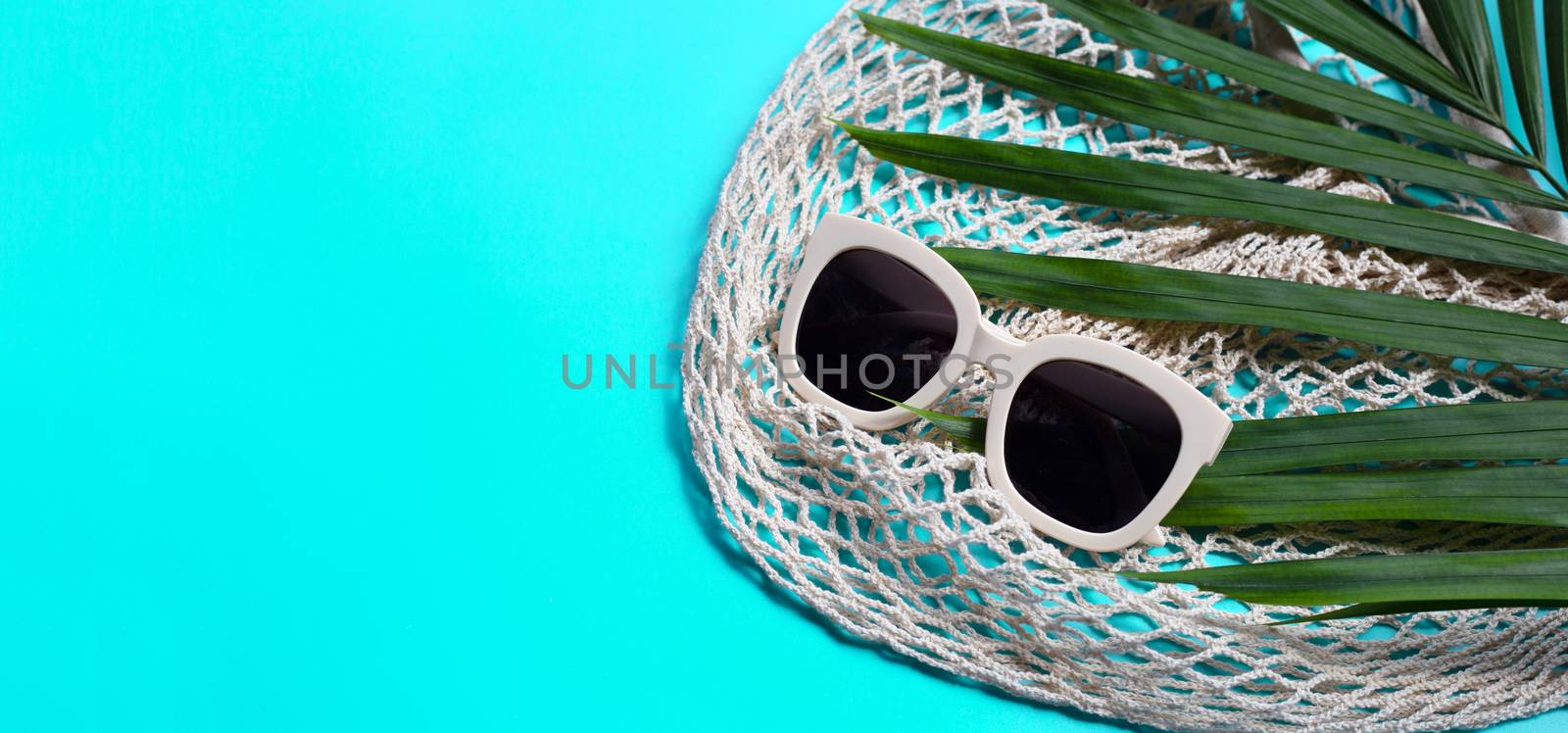 Sunglasses with mesh bag on blue background. Enjoy holiday conce by Bowonpat