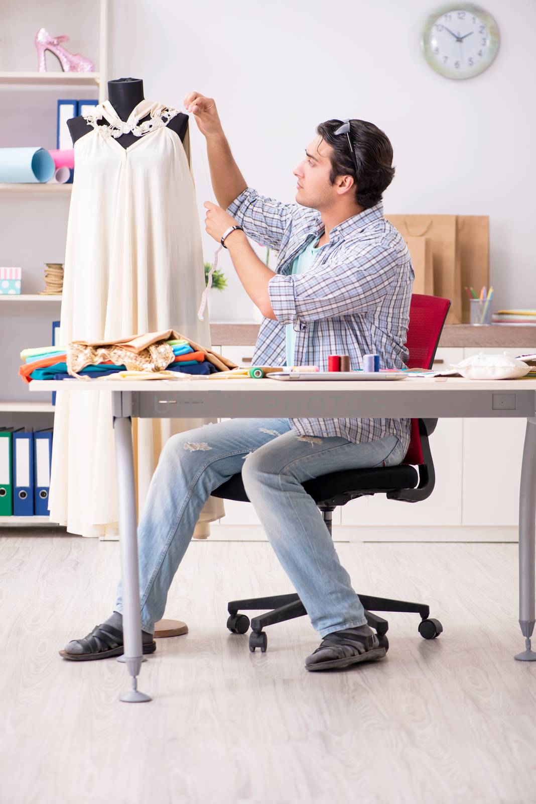 Young handsome tailor working in his workshop