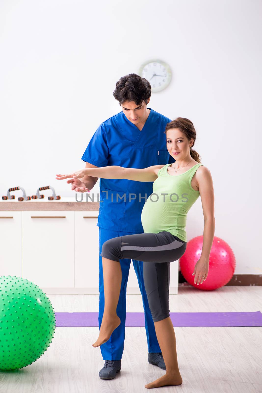 Pregnant woman doing physical exercies with instructor by Elnur