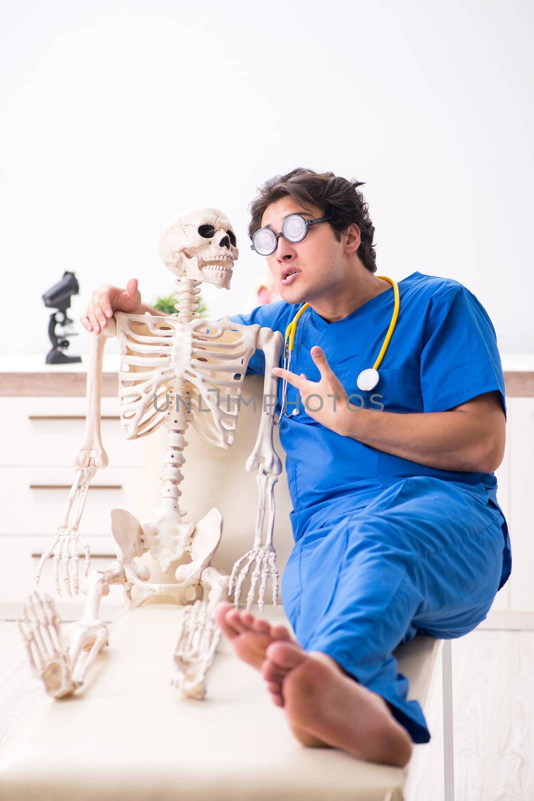 Funny doctor with skeleton in hospital