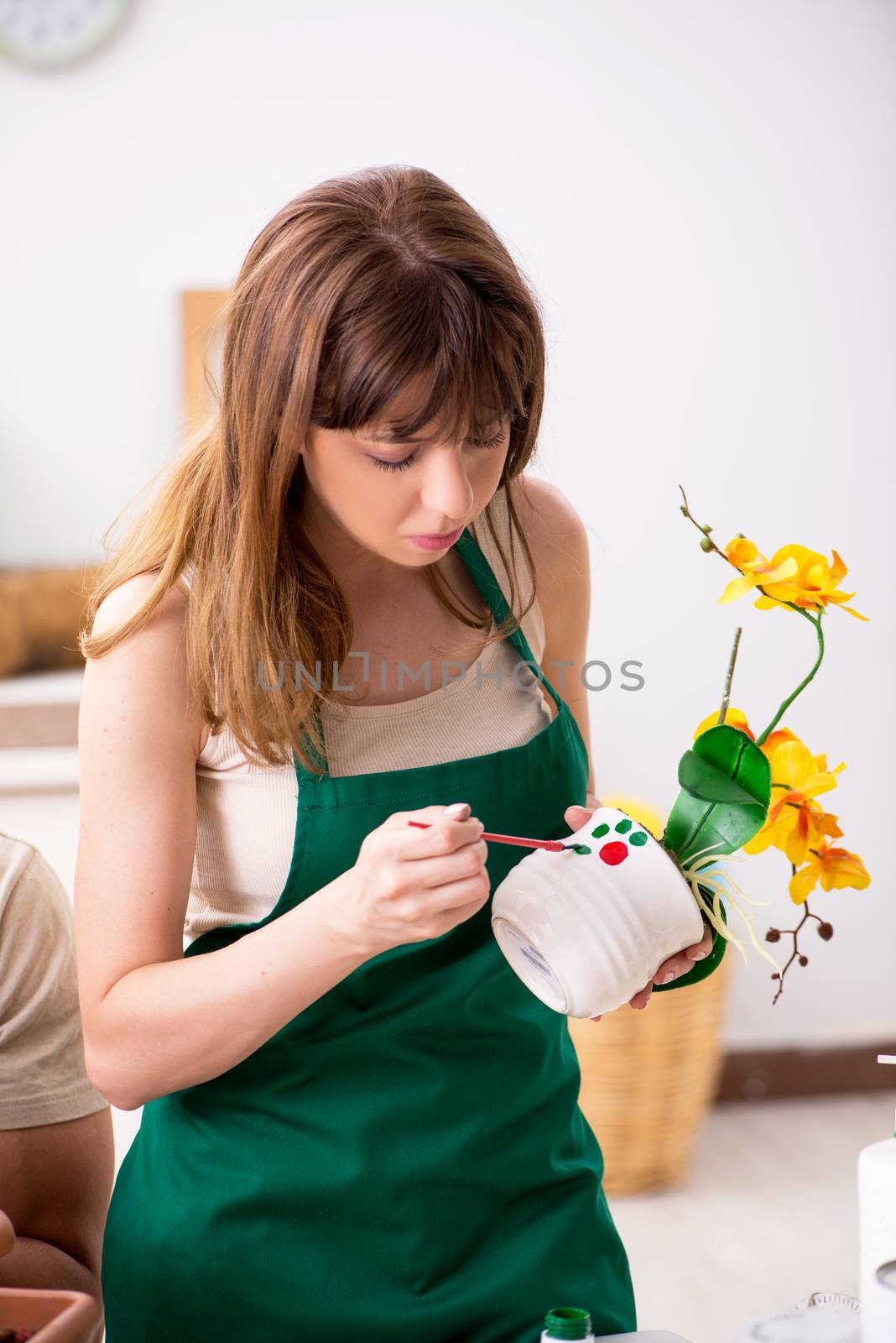 Young woman decorating pottery in workshop